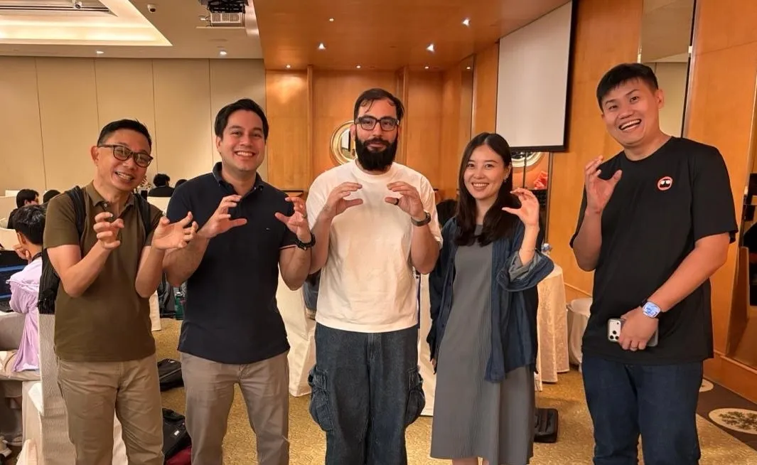 Group photo of Vincent Koc, YJ, and others making crab claw hand gestures